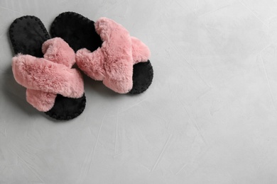 Pair of soft slippers on light grey background, flat lay. Space for text