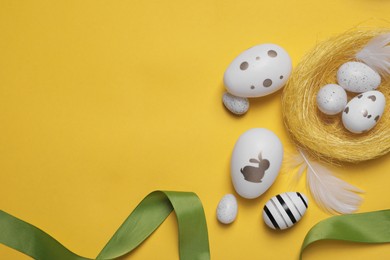 Photo of Flat lay composition with festively decorated Easter eggs on yellow background. Space for text