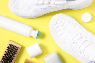 Flat lay composition with stylish footwear and shoe care accessories on yellow background