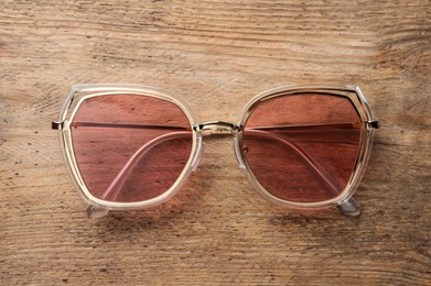 New stylish sunglasses on wooden table, top view