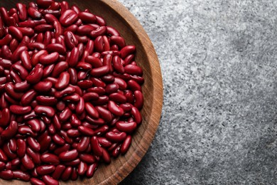 Raw red kidney beans in wooden bowl on grey table, top view. Space for text