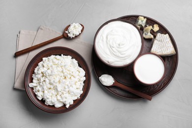 Clay dishware with fresh dairy products on grey table, flat lay