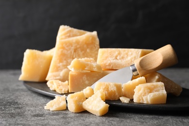 Parmesan cheese with board and knife on grey table, closeup