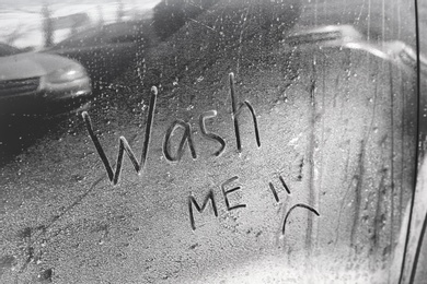 Inscription WASH ME and sad smiley on car door, closeup