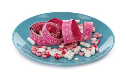 Plate with weight loss pills and measuring tape on white background