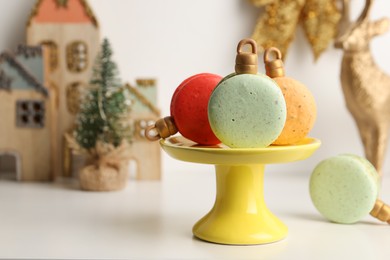 Stand with beautifully decorated Christmas macarons on white table, space for text