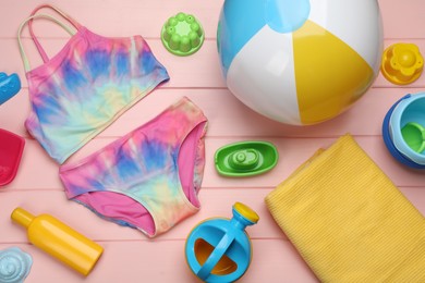 Flat lay composition with beach ball and sand toys on pink wooden background