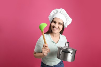 Photo of Happy young woman with cooking pot and ladle on pink background