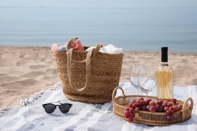 Bag, blanket, wine and other stuff for beach picnic on sandy seashore