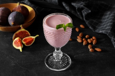 Delicious fig smoothie in glass on black table