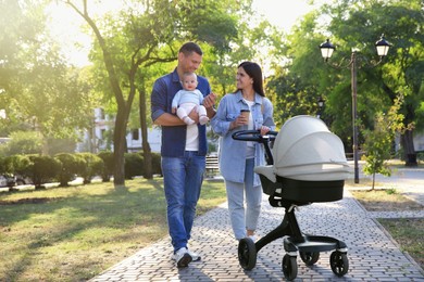 Happy parents walking with their baby in park on sunny day