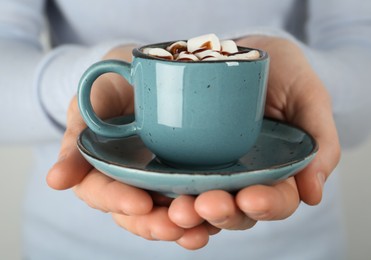 Woman holding cup of delicious hot chocolate with marshmallows and syrup, closeup