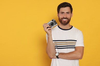Man with camera on yellow background, space for text. Interesting hobby