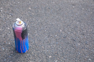 Used can of spray paint on asphalt road, space for text. Graffiti supplies