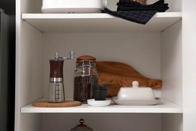 Manual coffee grinder and other appliances on shelving unit in kitchen