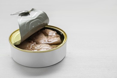 Photo of Open tin can of tasty cod liver on white wooden table, closeup. Space for text