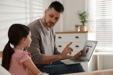 Dad installing parental control on laptop at home. Child safety