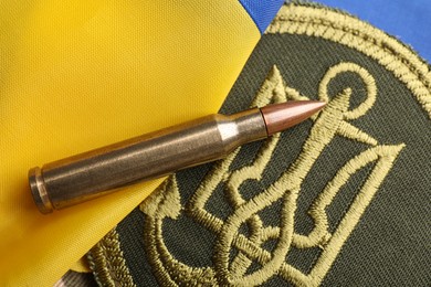 Photo of Bullet and military patch on Ukrainian flag, top view