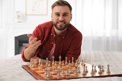 Happy young man playing chess on bed at home