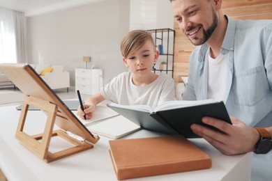 Boy with father doing homework at table indoors