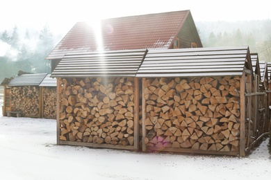 Photo of Wood sheds with stacked firewood outdoors on sunny winter day