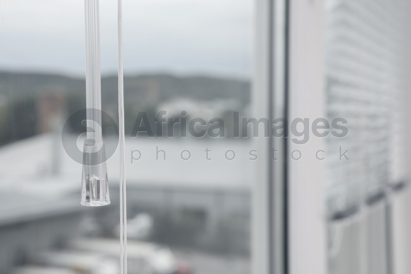 Photo of Stylish window with horizontal blinds indoors, focus on handle. Space for text