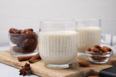 Photo of Glass of delicious date smoothie, dried fruits, spices and nuts on table
