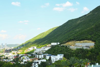 Photo of Beautiful view of city and green mountains on sunny day