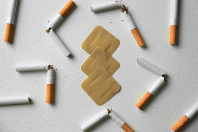 Nicotine patches and broken cigarettes on white background, flat lay