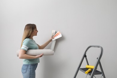 Woman with palette choosing wall paper color indoors