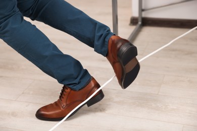 Photo of Man tripping over cord in office, closeup