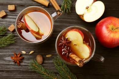 Aromatic hot mulled cider on black wooden table, flat lay
