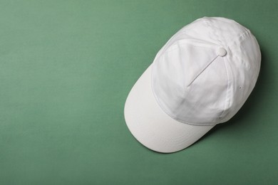 Baseball cap on green background, top view. Space for text