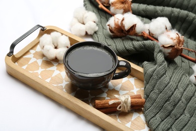 Composition with hot drink and warm plaid on white bedsheet