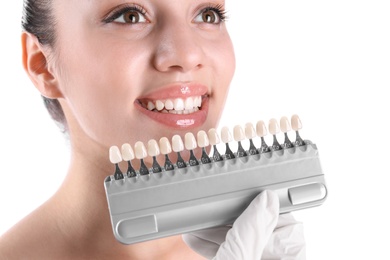 Photo of Dentist checking young woman's teeth color on white background, closeup