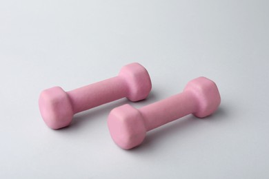 Two pink rubber coated dumbbells on light background