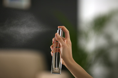 Photo of Woman spraying air freshener at home, closeup