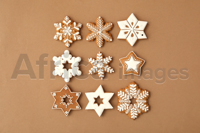 Christmas snowflake shaped gingerbread cookies on brown background, flat lay