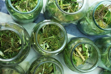 Glass jars with different herbs on table, flat lay. Pickling vegetables