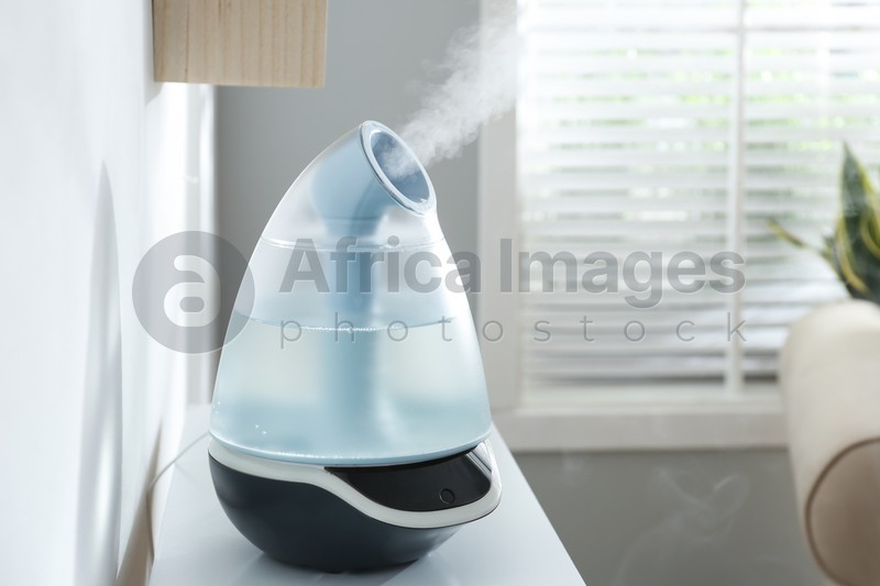 Modern air humidifier on table at home. Space for text