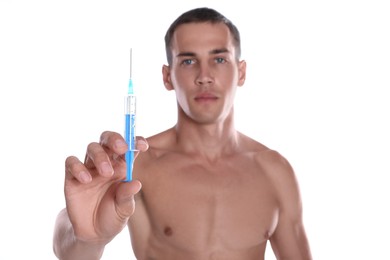 Athletic man with syringe against white background, focus on hand. Doping concept