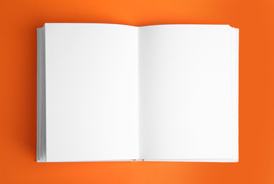 Open book with blank pages on orange background