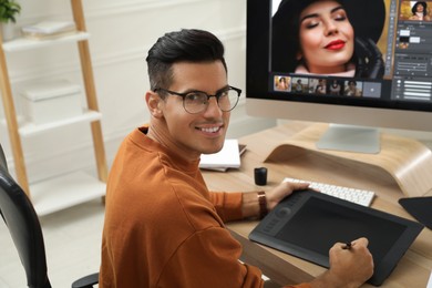 Professional retoucher working with graphic tablet at desk in office