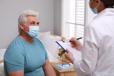 Doctor examining senior man with protective mask at nursing home
