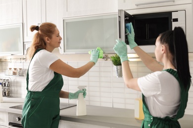 Team of professional janitors cleaning kitchen indoors