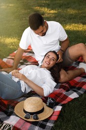 Lovely couple resting on picnic plaid in summer park