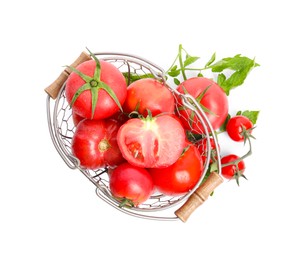 Many ripe tomatoes with leaves in metal basket on white background, top view