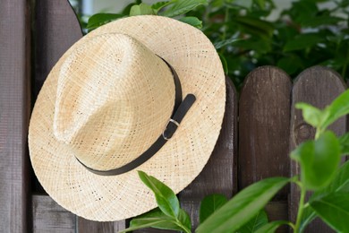 Stylish hat hanging on wooden fence. Beach accessory
