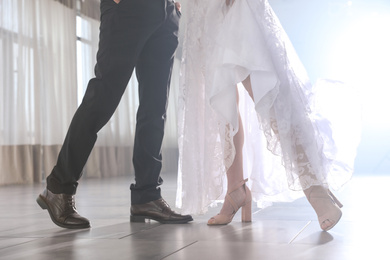 Newlywed couple dancing together in festive hall, closeup of legs
