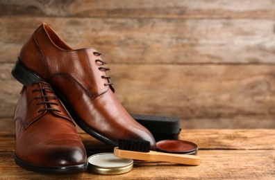 Shoe care products and footwear on wooden table. Space for text